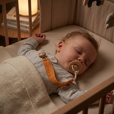 bébé qui dort et l'Attache tetine accrochés sur ces vêtements